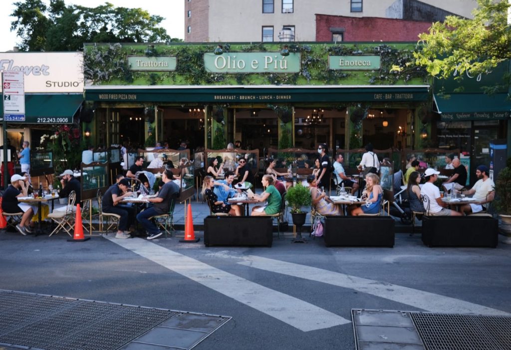 Comensales comiendo en mesas en los exteriores de un restaurante de Manhattan durante el verano
